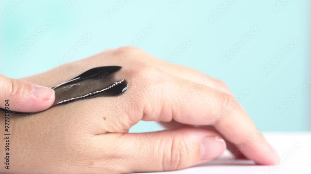 Swatch of black cream or black jelly mask for face on hand skin. Sample of clay or charcoal mud cream, macro Swatch of black cream or black jelly mask for face on hand skin. Sample of clay or charcoal mud cream, macro