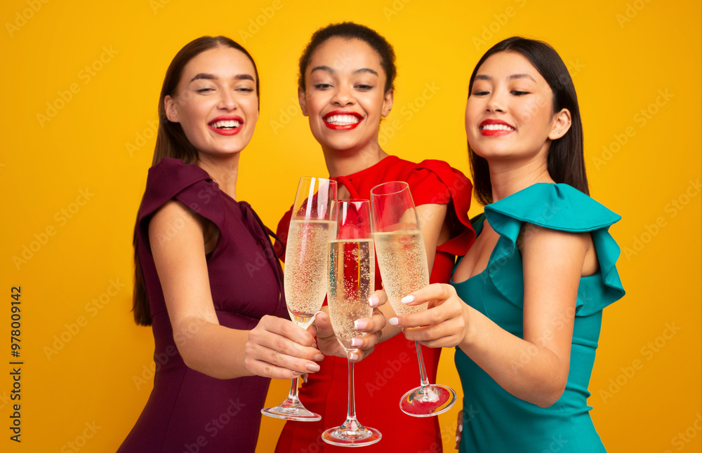 Three Girls With Champagne Having Party Toasting And Clinking Glasses Celebrating Something Standing In Studio On Yellow Background