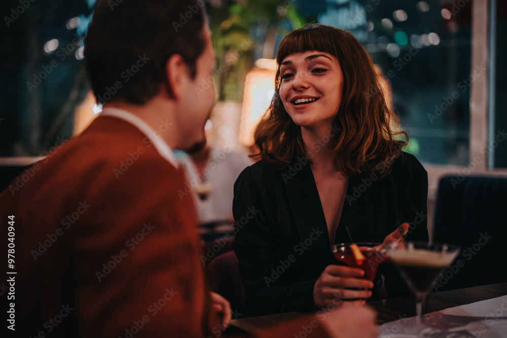 A cheerful woman sharing a lively conversation over cocktails with a friend in a dimly lit, cozy bar setting. A cheerful woman sharing a lively conversation over cocktails with a friend in a dimly lit, cozy bar setting.