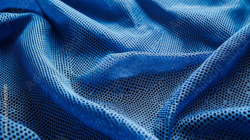 A bright blue sports fabric with visible mesh holes, designed for ventilation. The fabric is laid out with a few creases, allowing the texture to catch the light  photo