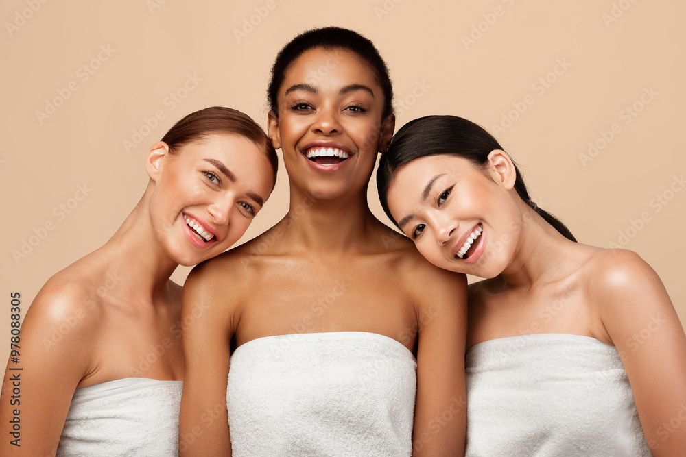 Beauty And Spa. Three Positive Pretty Girls Wrapped In Bath Towels Posing After Shower On Gray Background In Studio