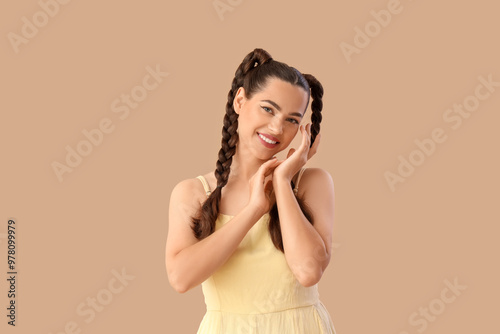 Beautiful young happy stylish woman with braids on beige background