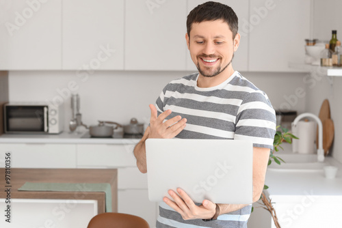 Young male teacher with laptop giving online lesson at home