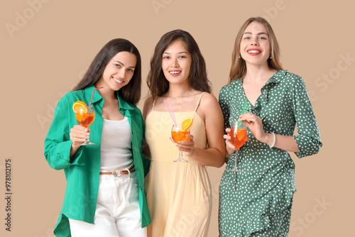 Young women with aperol spritz cocktail on beige background
