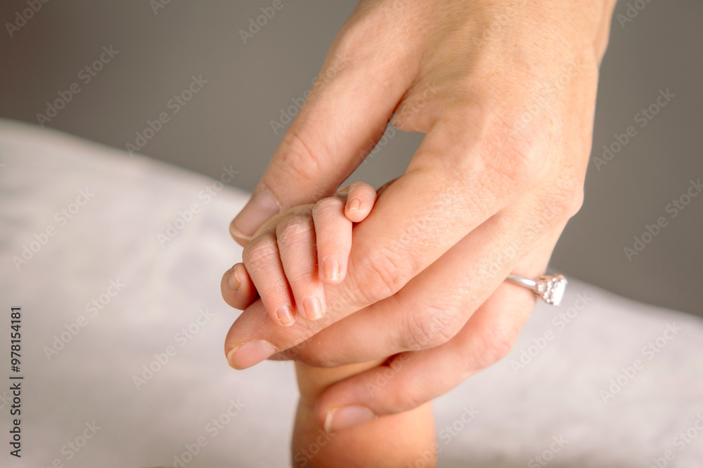 Close up of an infant's hand held by a mother's hand wearing a wedding ring Close up of an infant's hand held by a mother's hand wearing a wedding ring