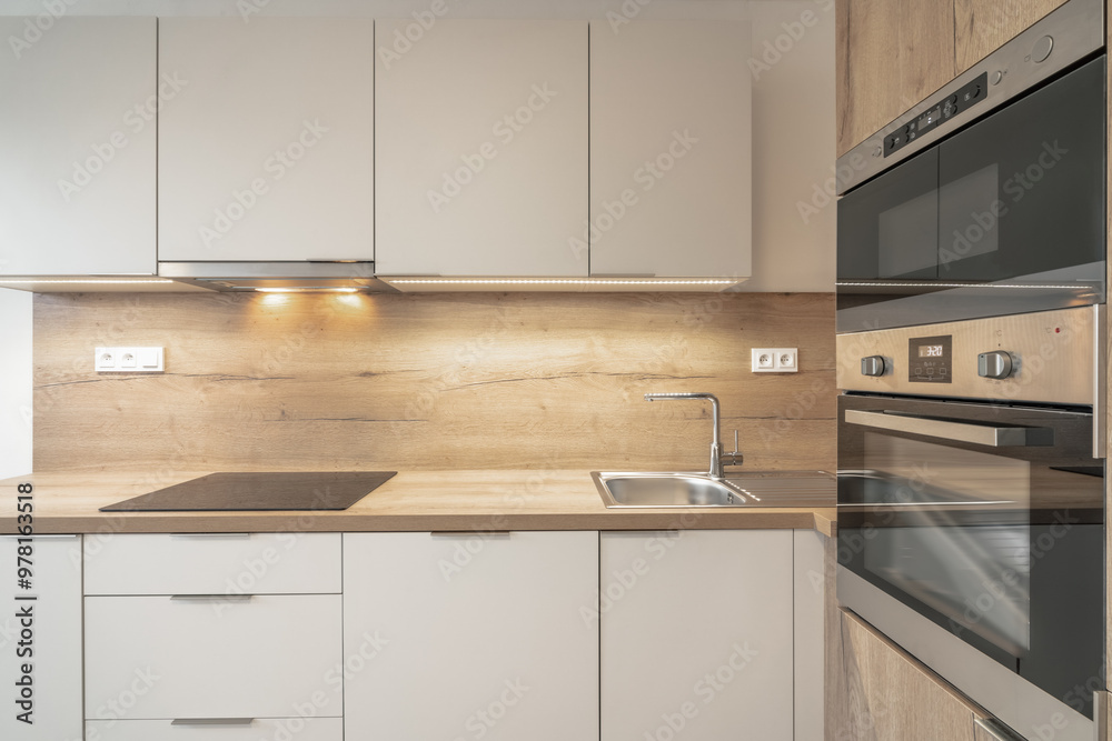 A modern kitchen with wooden countertops, cabinets, an oven, microwave, sink, and stovetop. The kitchen has a contemporary design with integrated appliances and under-cabinet lighting. A modern kitchen with wooden countertops, cabinets, an oven, microwave, sink, and stovetop. The kitchen has a contemporary design with integrated appliances and under-cabinet lighting.