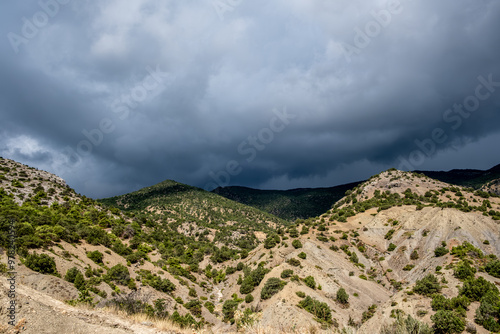 Hills covered with forest against the background of clouds.