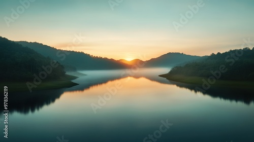 Serene sunrise over a tranquil lake surrounded by misty hills. A perfect moment captured in nature's beauty and peaceful reflection.