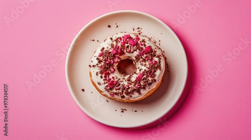 Top view of a decadent tiramisu doughnut with messy toppings on a plate, against a bright pink background, showcasing dessert indulgence