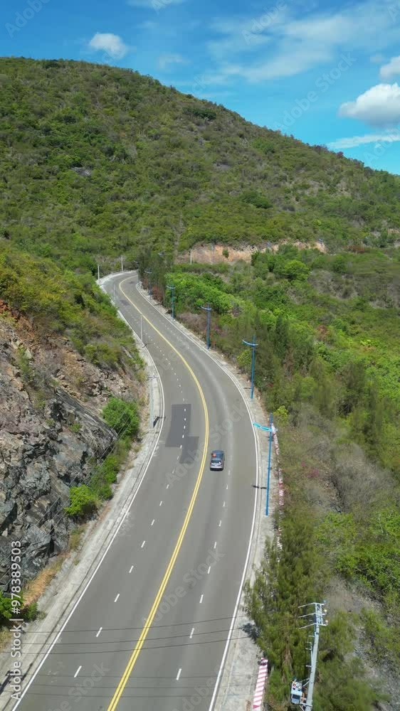 Ready for a adventure road trip between a mountain and the ocean. Driving alone on a coast road. Aerial view of a car driven on an amazing curved waving road at the Sea shore in Nha Trang, Vietnam Ready for a adventure road trip between a mountain and the ocean. Driving alone on a coast road. Aerial view of a car driven on an amazing curved waving road at the Sea shore in Nha Trang, Vietnam