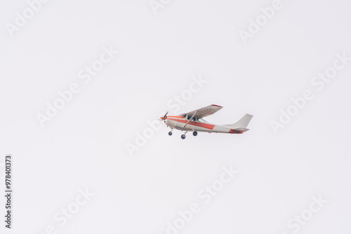 Small ultralight airplane with overhead wing and single propeller flying in sunset sky.
