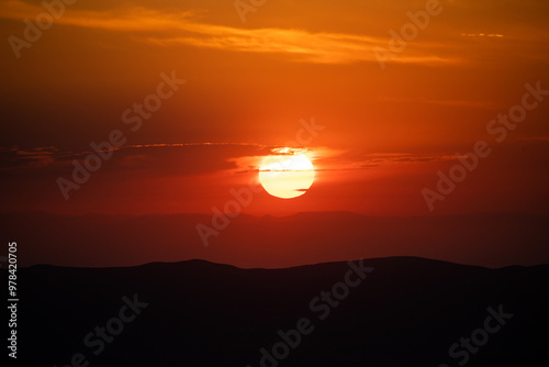 Fototapeta Naklejka Na Ścianę i Meble -  deep orange sunrise over layered mountains