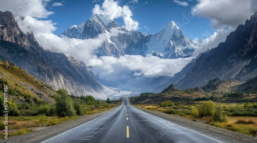 Cloud-covered Passu Cones stand tall as the Karakoram Highway winds through the peaceful Hunza Valley, with the road stretching into the distance.