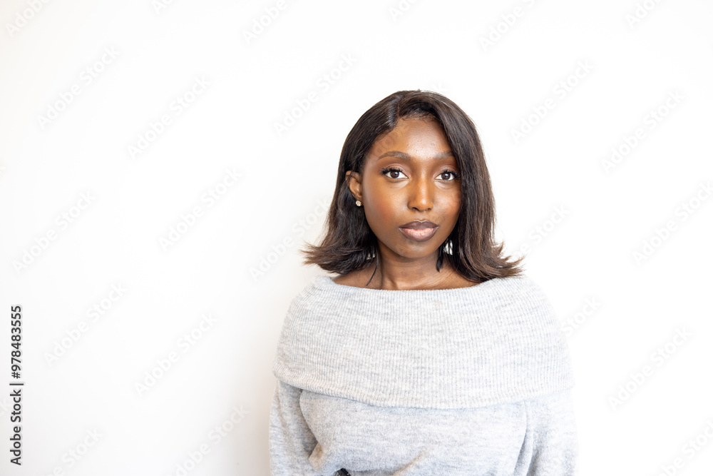 A young woman with a confident expression posing against a plain white background wearing a grey sweater. A young woman with a confident expression posing against a plain white background wearing a grey sweater.