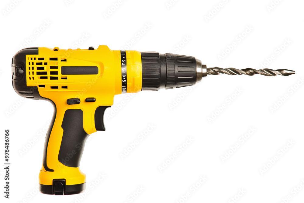 Yellow cordless drill with a twisting metal drill bit ready for use in a workshop. Yellow cordless drill with a twisting metal drill bit ready for use in a workshop.