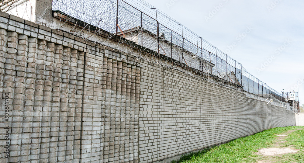 Fototapeta premium Brick Prison Wall with Barbed Wire