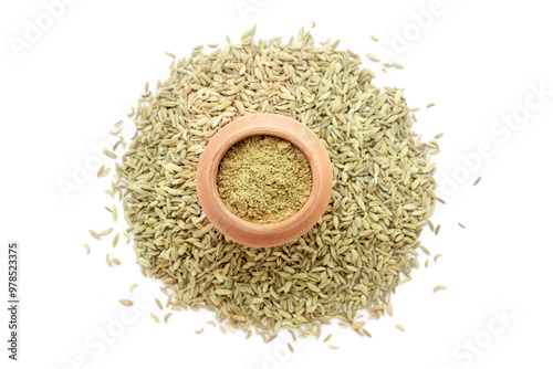 A mud pot filled with organic Fennel Seeds (Foeniculum vulgare) Badi saunf powder, placed over a heap of Fennel Seeds, isolated on a white background. photo