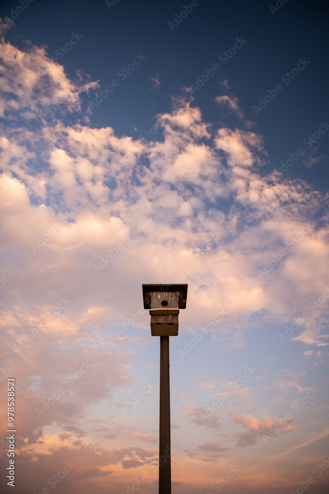 birdhouse stands tall with beautiful sunset clouds birdhouse stands tall with beautiful sunset clouds
