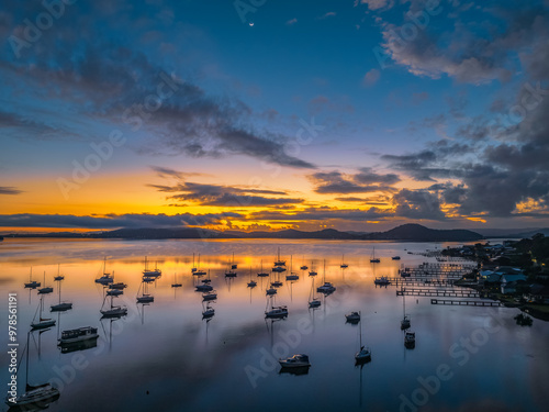 Aerial sunrise waterscape with boats, clouds and fog over the mountain range