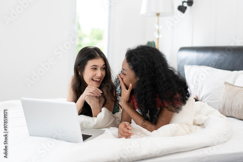 Happy lesbian couple having and using laptop in bedroom