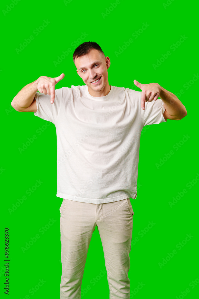 Young Man in a White Shirt Pointing Downward Against a Bright Green Background Young Man in a White Shirt Pointing Downward Against a Bright Green Background