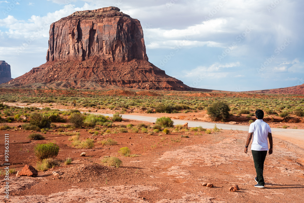 A man stands gazing at Monument Valley's iconic butte in the distance. A man stands gazing at Monument Valley's iconic butte in the distance.
