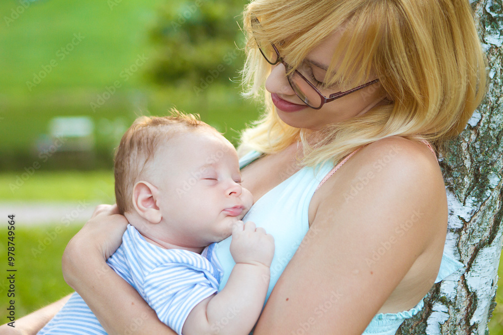 A tender moment of a mother embracing her sleeping baby under golden sunlight in a serene park setting A tender moment of a mother embracing her sleeping baby under golden sunlight in a serene park setting