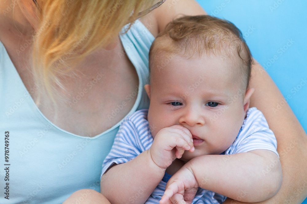 A young child, dressed in stripes, gently sucks on his thumb while being held by a loving parent. The warm sunlight enhances their tender moment. A young child, dressed in stripes, gently sucks on his thumb while being held by a loving parent. The warm sunlight enhances their tender moment.