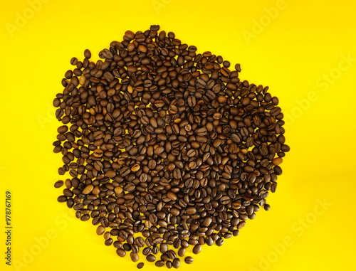 Natural roasted coffee beans on a sunny yellow background