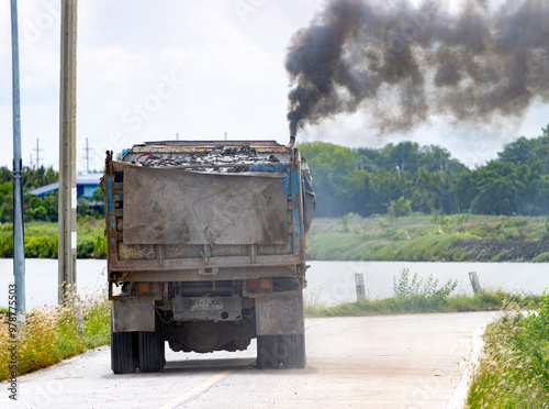 A loaded truck ride on the road with thick black smoke from the exhaust