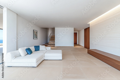 Modern minimalist living room with a sectional sofa and large windows offering ocean views in a contemporary house