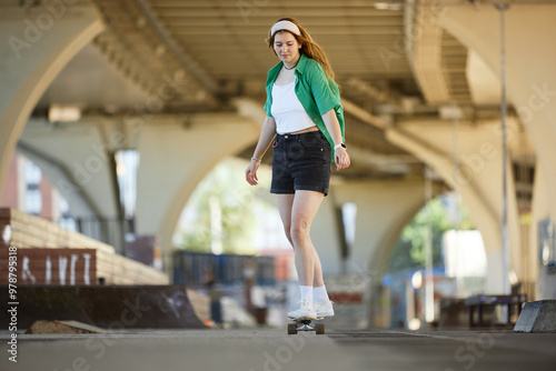 Person skateboarding under an urban bridge wearing casual outfit and headband. Scene filled with architectural structures and vibrant environment reflecting dynamic atmosphere