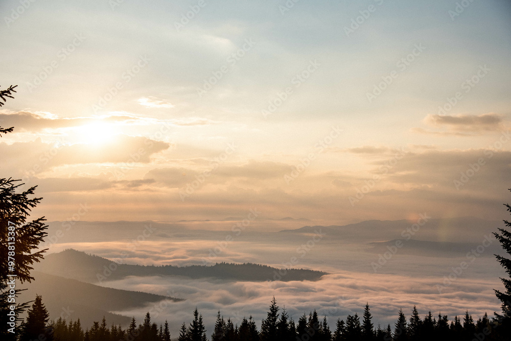 Fototapeta premium Majestic Mountain Landscape Covered in Mist with Sun Rays Breaking Through Clouds