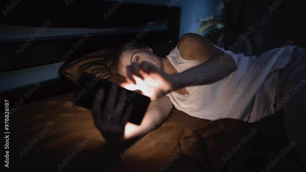 Mature woman in bed late at night with amazed face expression using mobile phone watching online movie or reading message enjoying alone in internet addiction Mature woman in bed late at night with amazed face expression using mobile phone watching online movie or reading message enjoying alone in internet addiction