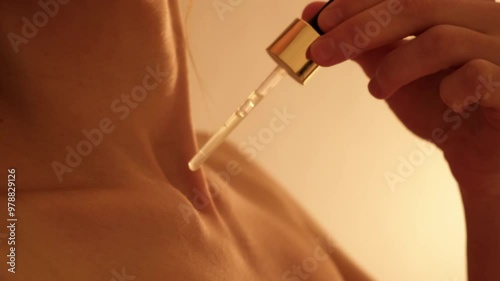 Skin care. Sexy woman dripping aromatic oil on her chest. A drop runs down the girl's body close-up. Using an aphrodisiac. Side view. Youth serum. Love potion. Moisturizing body lotion. Sensitive joy photo