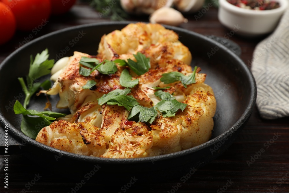 Tasty cauliflower steak and parsley in frying pan on wooden table, closeup Tasty cauliflower steak and parsley in frying pan on wooden table, closeup
