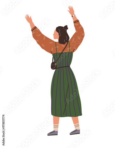 Woman with a bun hairstyle standing with arms raised joyfully. Wearing a green dress with stripes, brown top, black crossbody bag, and casual shoes. Ideal for happiness, freedom, fashion