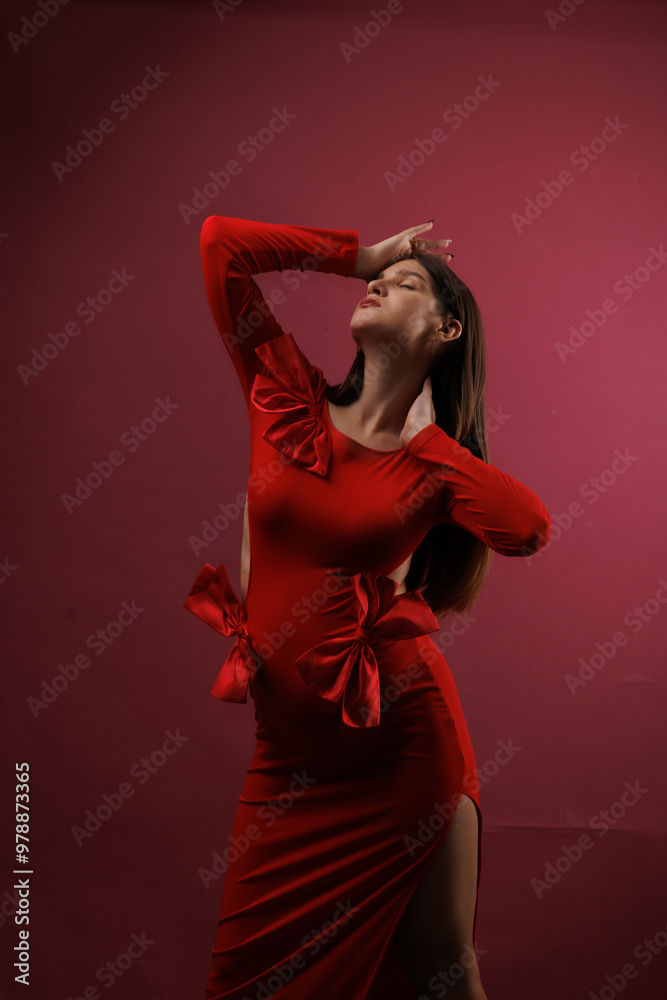 Beautiful young pregnant brunette girl. A woman waiting for a baby in a red dress with bows, on red background, in the studio. Beautiful young pregnant brunette girl. A woman waiting for a baby in a red dress with bows, on red background, in the studio.