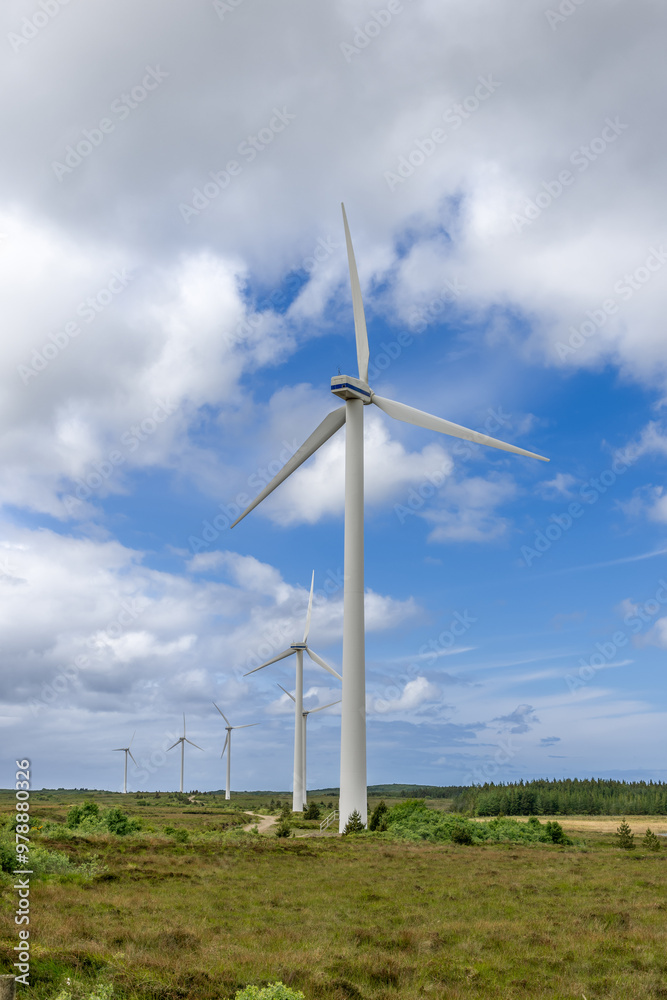 Wind turbines stretch into the horizon under a vast sky and over green fields in Ireland, captured in a vertical frame Wind turbines stretch into the horizon under a vast sky and over green fields in Ireland, captured in a vertical frame