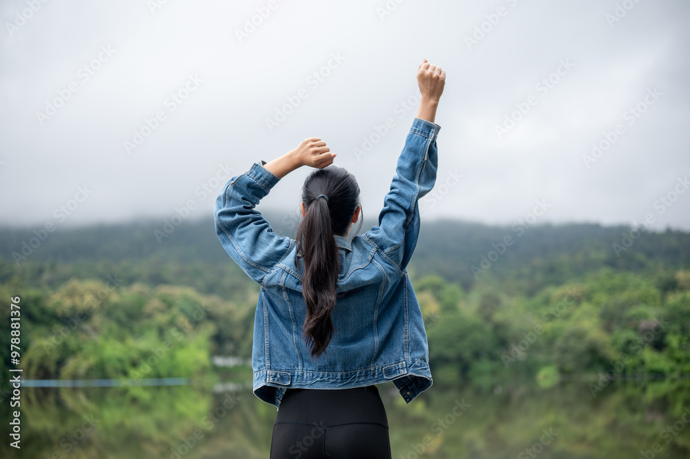 A carefree Asian woman raising her hand as she looks at a stunning mountain and lake view. A carefree Asian woman raising her hand as she looks at a stunning mountain and lake view.