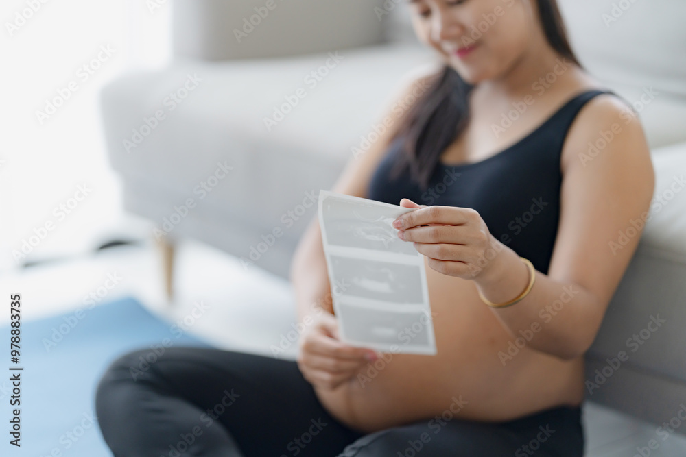 Happy pregnant asian woman holding ultrasound baby picture Result from Doctor at home Happy pregnant asian woman holding ultrasound baby picture Result from Doctor at home