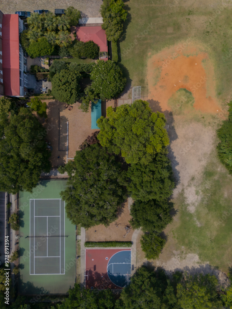 Aerial view of tennis and basketball courts surrounded by greenery and urban buildings, Charlestowne, South Carolina, United States. Aerial view of tennis and basketball courts surrounded by greenery and urban buildings, Charlestowne, South Carolina, United States.
