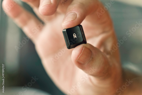A hand holding a key with the spanish letter Ñ (N with a tilde) on it photo