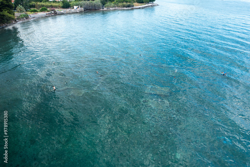 Aerial view of tranquil azure coastline with crystal clear water and serene reflections, Archea Epidavros, Greece. photo