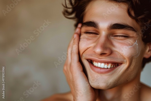 A handsome young man checking the skin on his face and smiling