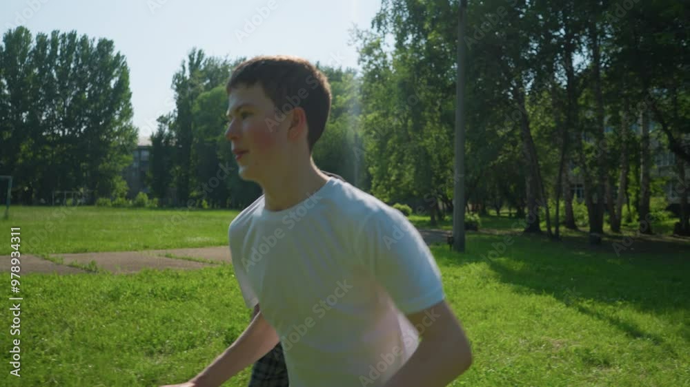 A young boy runs across a grassy field, full of energy, while his grandfather stands near by, with a goalpost in the background A young boy runs across a grassy field, full of energy, while his grandfather stands near by, with a goalpost in the background