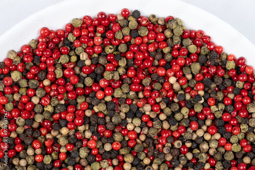 A mixture of different peppercorns on a white background, top view A mixture of different peppercorns on a white background, top view