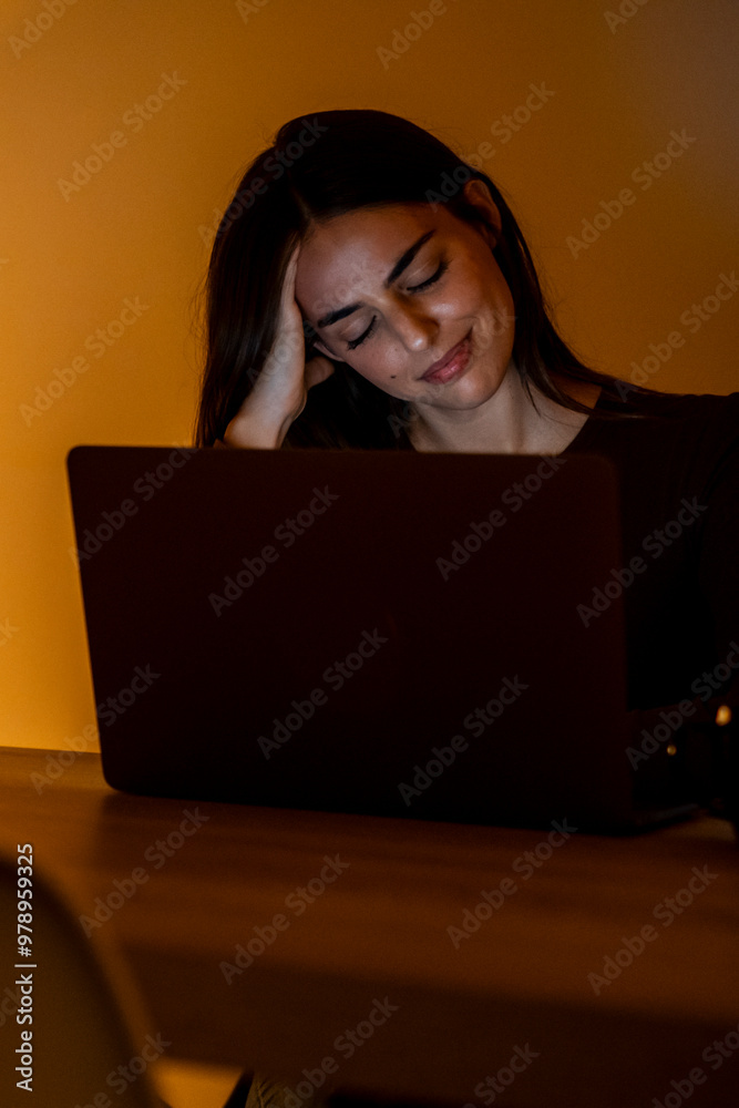 Late-night portrait of a tired and exhausted woman working on her laptop, showing boredom and frustration. Alone at home, she struggles with insomnia while staring at the computer, unable to sleep Late-night portrait of a tired and exhausted woman working on her laptop, showing boredom and frustration. Alone at home, she struggles with insomnia while staring at the computer, unable to sleep