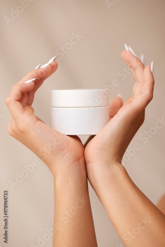 Hands holding a cream jar in a skin care setting photo