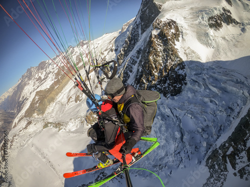 Skier paragliding over snow-covered mountains in winter